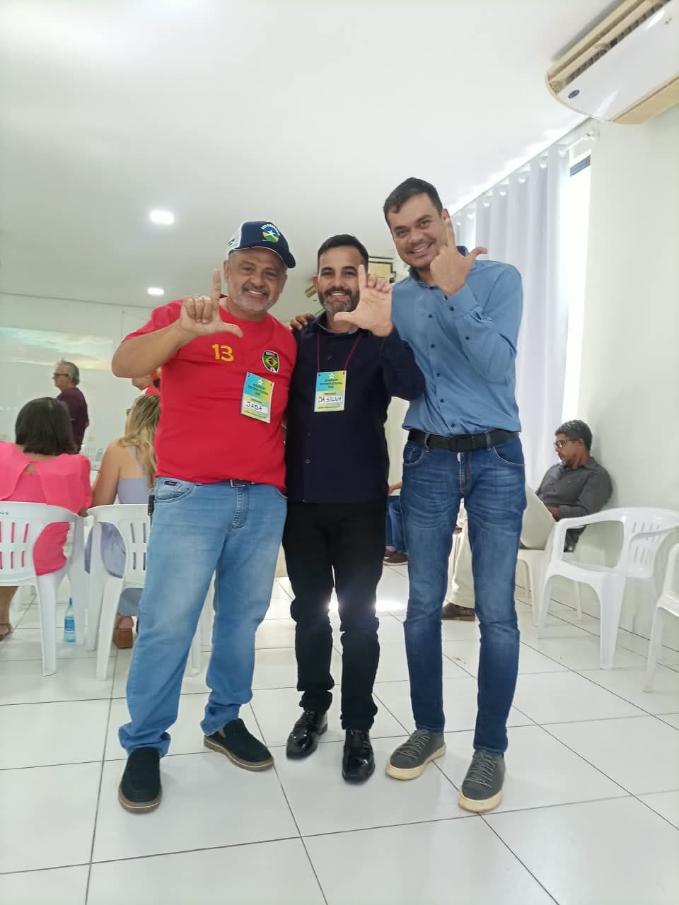 Dasilva ao centro, junto a dois participantes em um encontro.